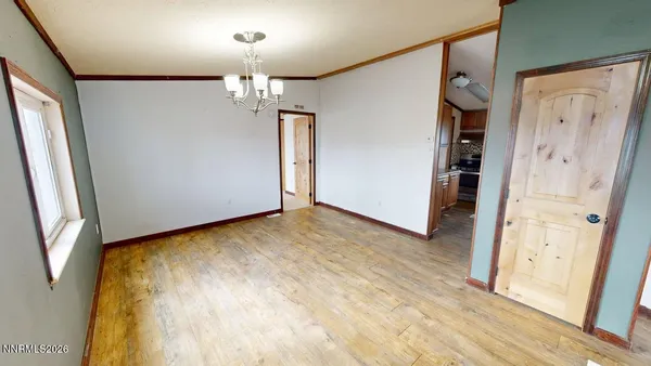 an empty room with wooden floor chandelier and windows