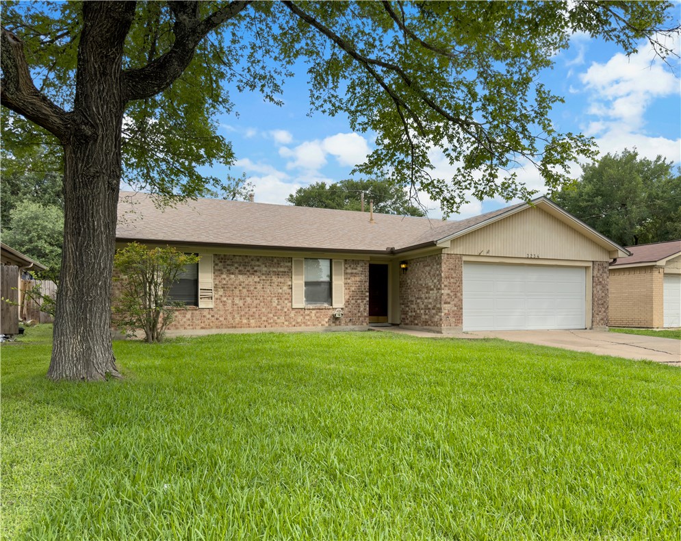 Ranch-style home featuring a garage, a front lawn, and brick siding