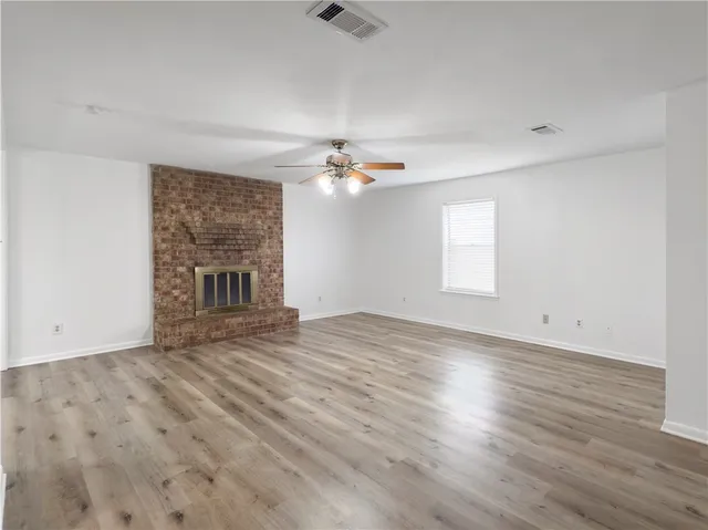 an empty room with wooden floor fireplace and windows