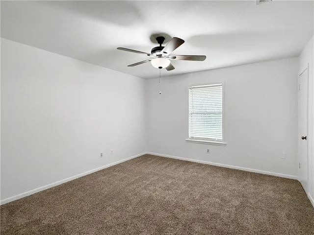 an empty room with a window and ceiling fan