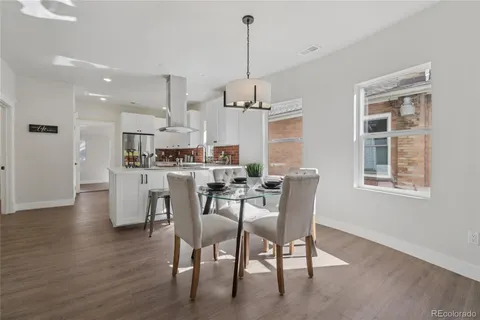 a dining room with wooden floor a chandelier a glass table and chairs
