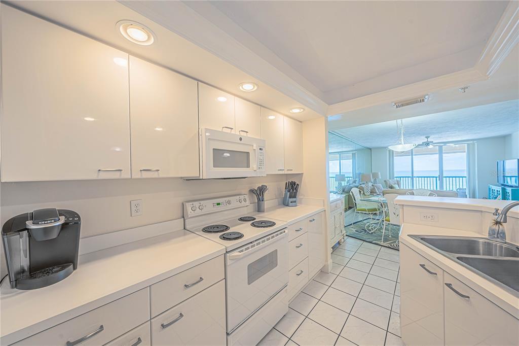 4575 South Atlantic Avenue, Unit 6607 Ponce Inlet, FL 32127 - Photo 13 of 48 a kitchen with a sink dishwasher a stove and white cabinets with wooden floor