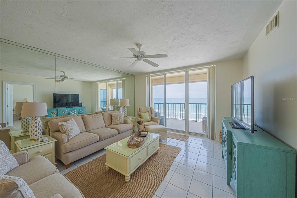 4575 South Atlantic Avenue, Unit 6607 Ponce Inlet, FL 32127 - Photo 8 of 48 a living room with furniture a large window and a chandelier