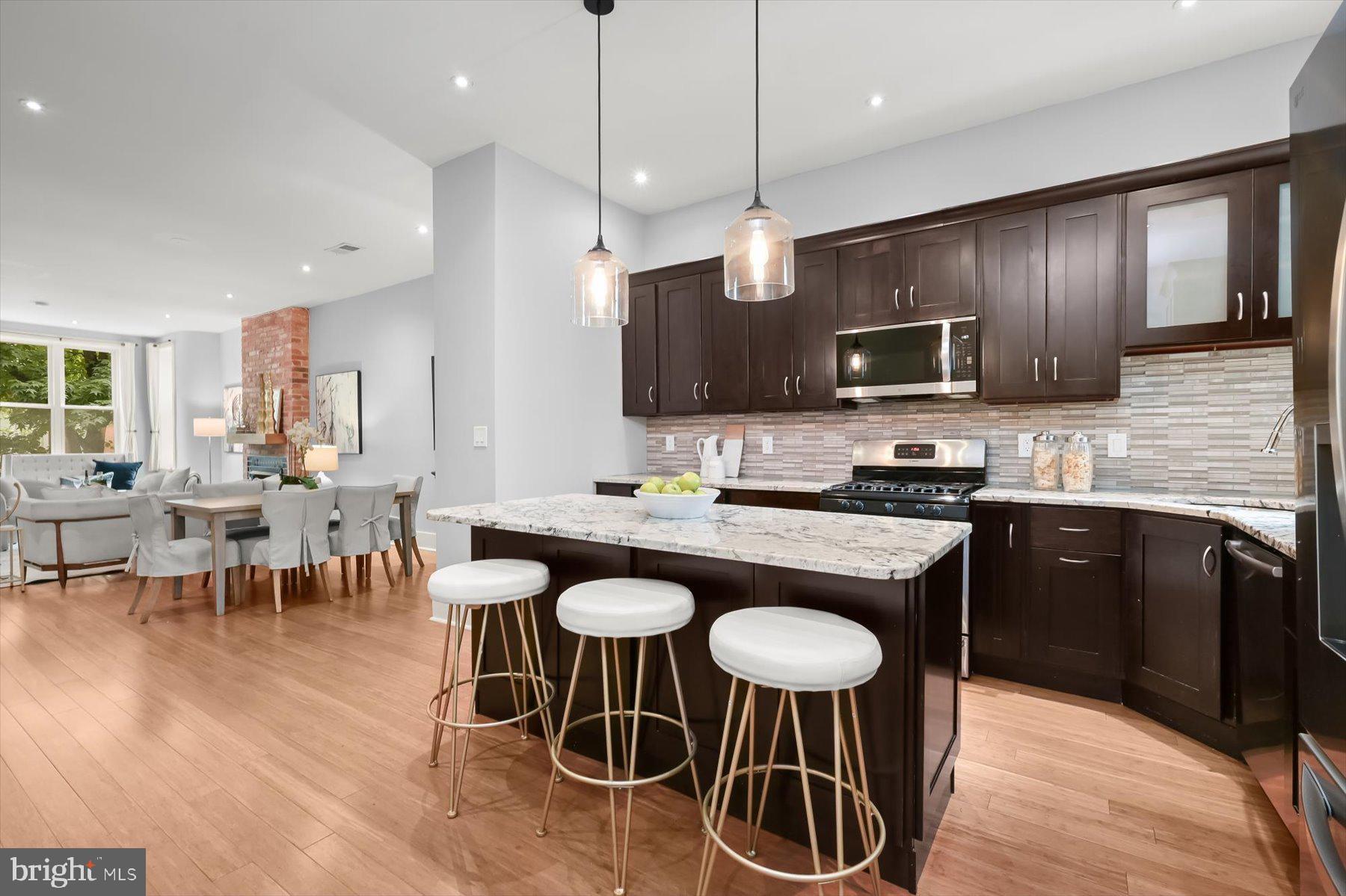 2128 1st Street Northwest, Unit 1 Washington, DC 20001 - Photo 11 of 36 a kitchen with stainless steel appliances granite countertop a stove a sink a microwave a dining table and chairs