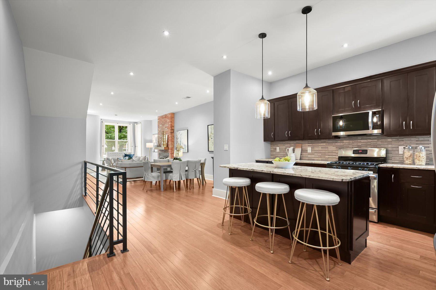 2128 1st Street Northwest, Unit 1 Washington, DC 20001 - Photo 17 of 36 a kitchen with stainless steel appliances granite countertop a stove a refrigerator a kitchen island a dining table and chairs with wooden floor