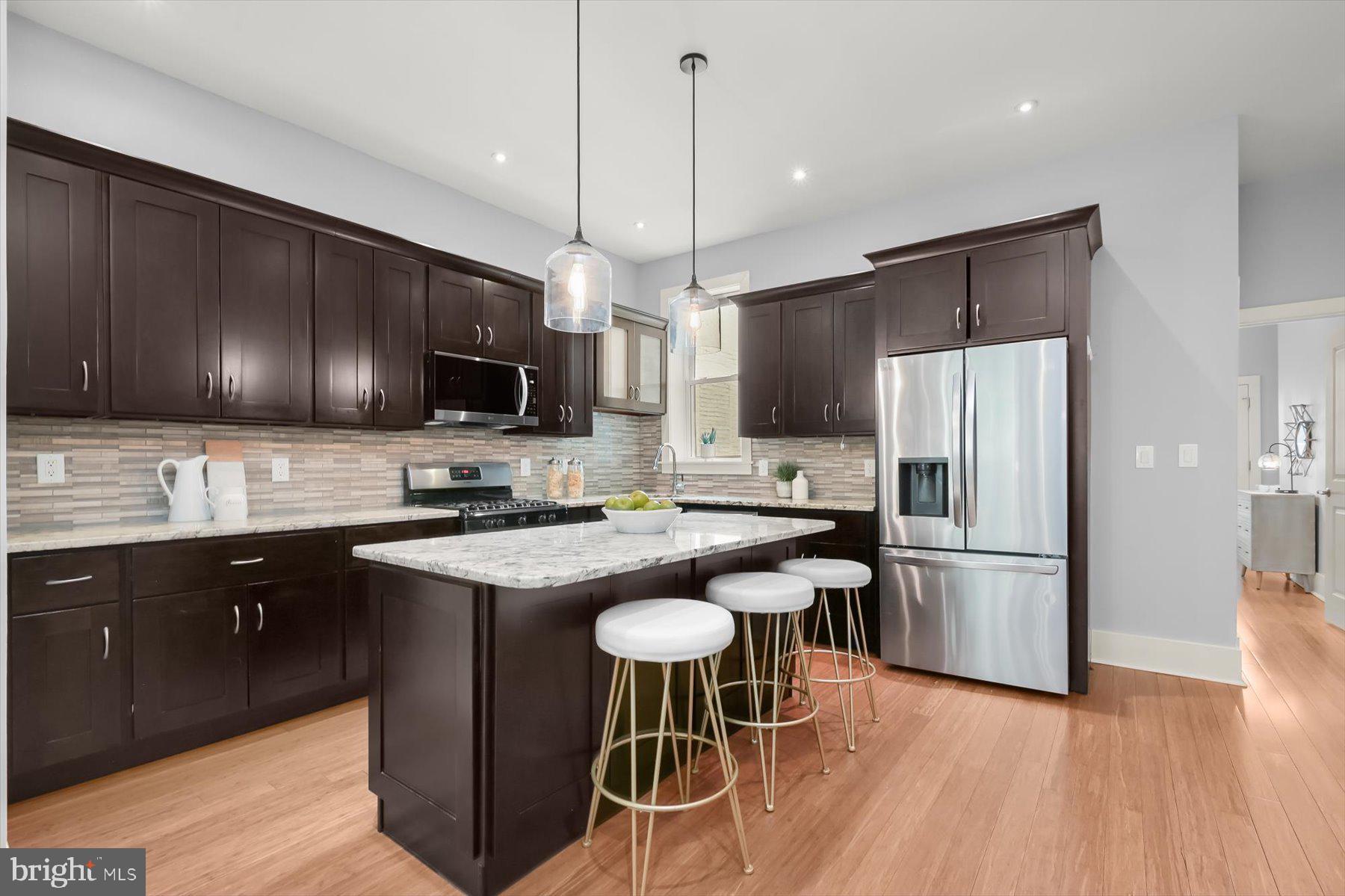 2128 1st Street Northwest, Unit 1 Washington, DC 20001 - Photo 9 of 36 a kitchen with kitchen island granite countertop a sink stove a refrigerator and microwave with wooden floor