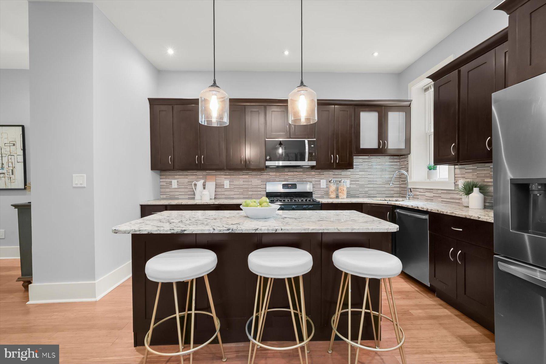2128 1st Street Northwest, Unit 1 Washington, DC 20001 - Photo 10 of 36 a kitchen with stainless steel appliances granite countertop a stove a sink island and chairs in it