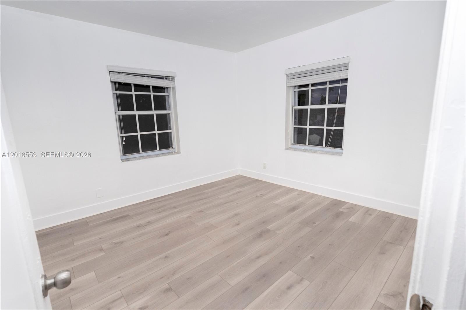 111 Southwest 31st Court Miami, FL 33135 - Photo 6 of 27 an empty room with wooden floor and windows
