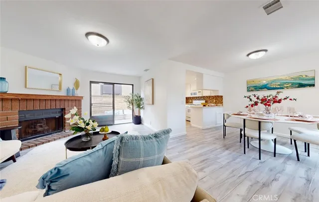 a living room with furniture a fireplace and a dining table with wooden floor