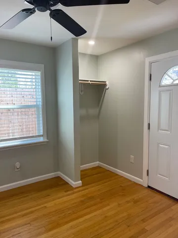 an empty room with wooden floor cabinet and windows