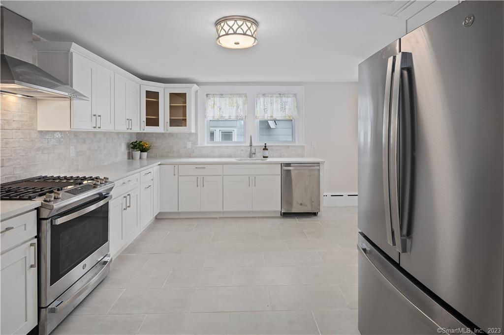 a large white kitchen with a stove top oven a sink and dishwasher