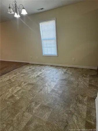 an empty room with a chandelier fan and windows