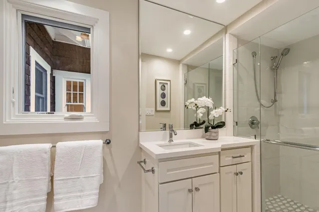 a spacious bathroom with a double vanity sink a mirror and a shower