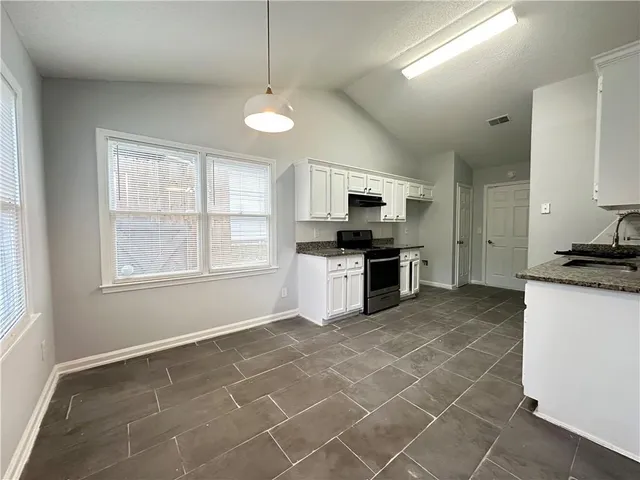 a kitchen with granite countertop a stove a sink and a refrigerator