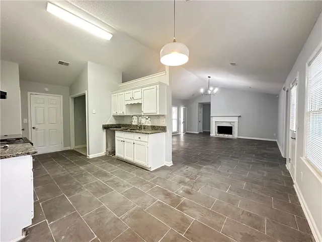 a view of kitchen with granite countertop cabinets and refrigerator