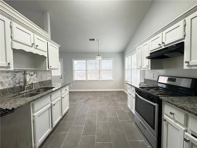 a kitchen with stainless steel appliances granite countertop a sink stove and cabinets