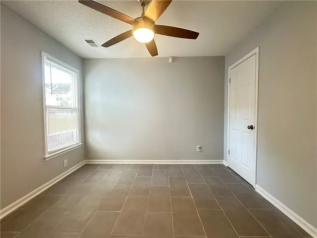 an empty room with windows and fan