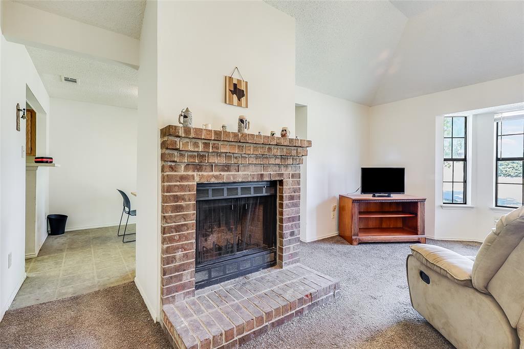 1728 Hackamore Street Mesquite, TX 75149 - Photo 4 of 22 Living area featuring a brick fireplace, light colored carpet, lofted ceiling, and a textured ceiling