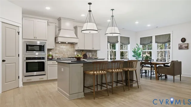 a kitchen with stainless steel appliances granite countertop a stove a sink a island a refrigerator a center island a stove and a wooden floors