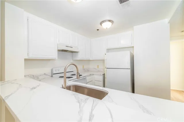 a kitchen with a sink a refrigerator and cabinets