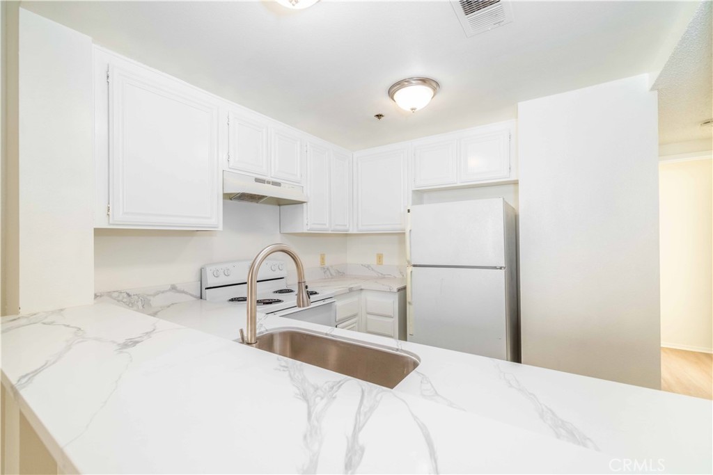 730 West 4th Street, Unit 413 Long Beach, CA 90802 - Photo 6 of 16 a kitchen with a sink a refrigerator and cabinets