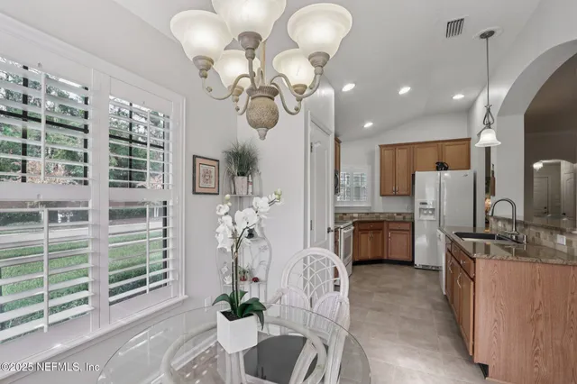 a kitchen with stainless steel appliances granite countertop a refrigerator a oven a sink and a dining table with wooden floor