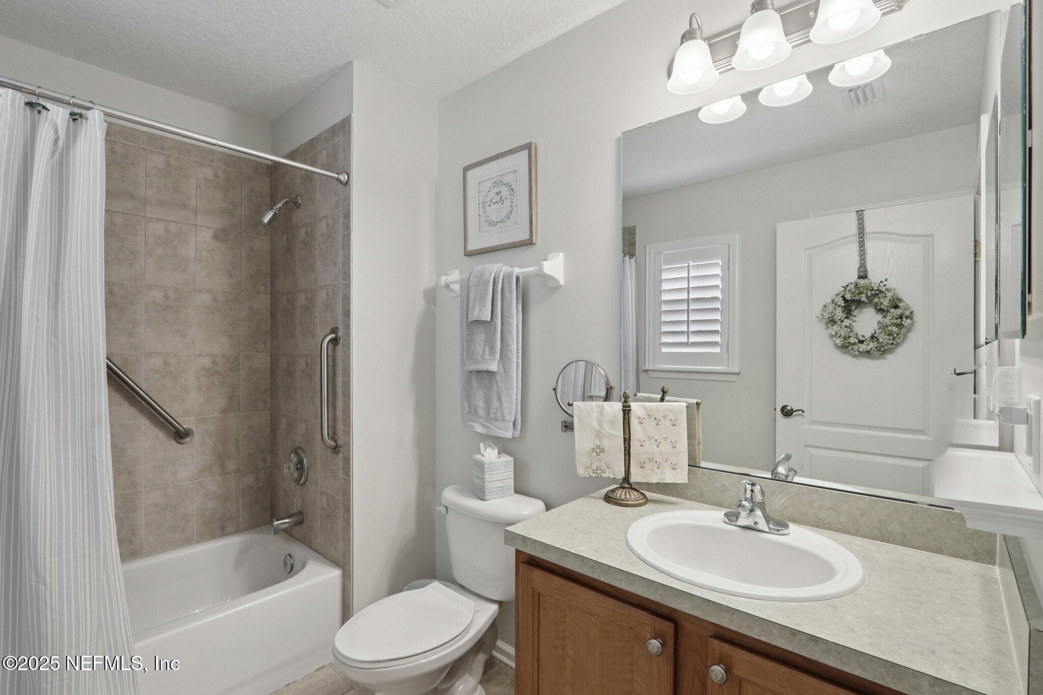 1870 Copper Stone Drive, Unit F Fleming Island, FL 32003 - Photo 25 of 36 a bathroom with a sink a toilet and a mirror