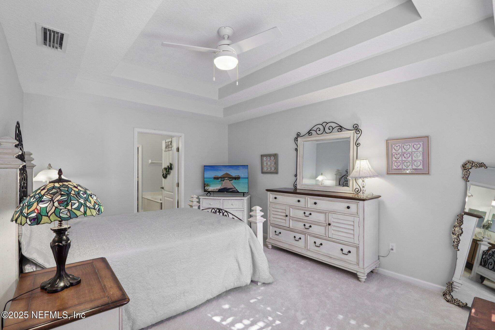 1870 Copper Stone Drive, Unit F Fleming Island, FL 32003 - Photo 26 of 36 a bedroom with a bed and a chandelier