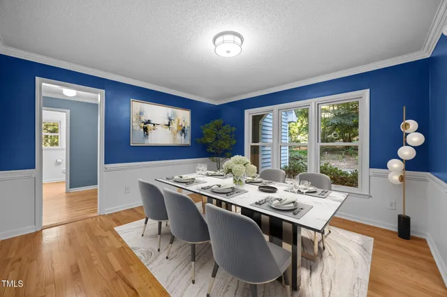 a dining room with wooden floor and large windows