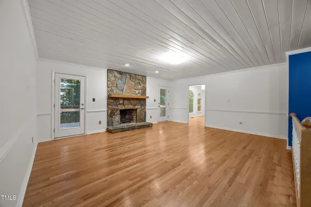 a view of empty room with wooden floor and fireplace
