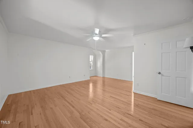 an empty room with wooden floor and fan