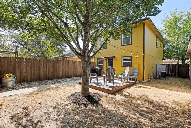 a view of a house with wooden fence and a tree