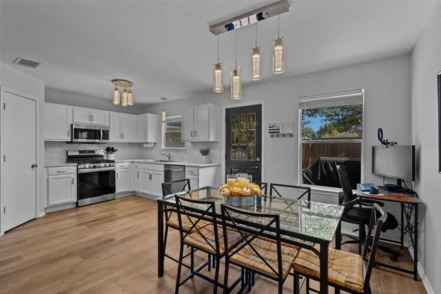 a kitchen with stainless steel appliances kitchen island granite countertop a dining table chairs stove and refrigerator