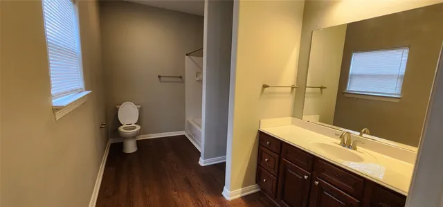 a bathroom with a sink a toilet a shower and a window