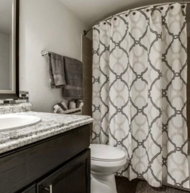 9407 Westheimer Road, Unit 305 Houston, TX 77063 - Photo 8 of 10 a bathroom with a granite countertop sink and a toilet