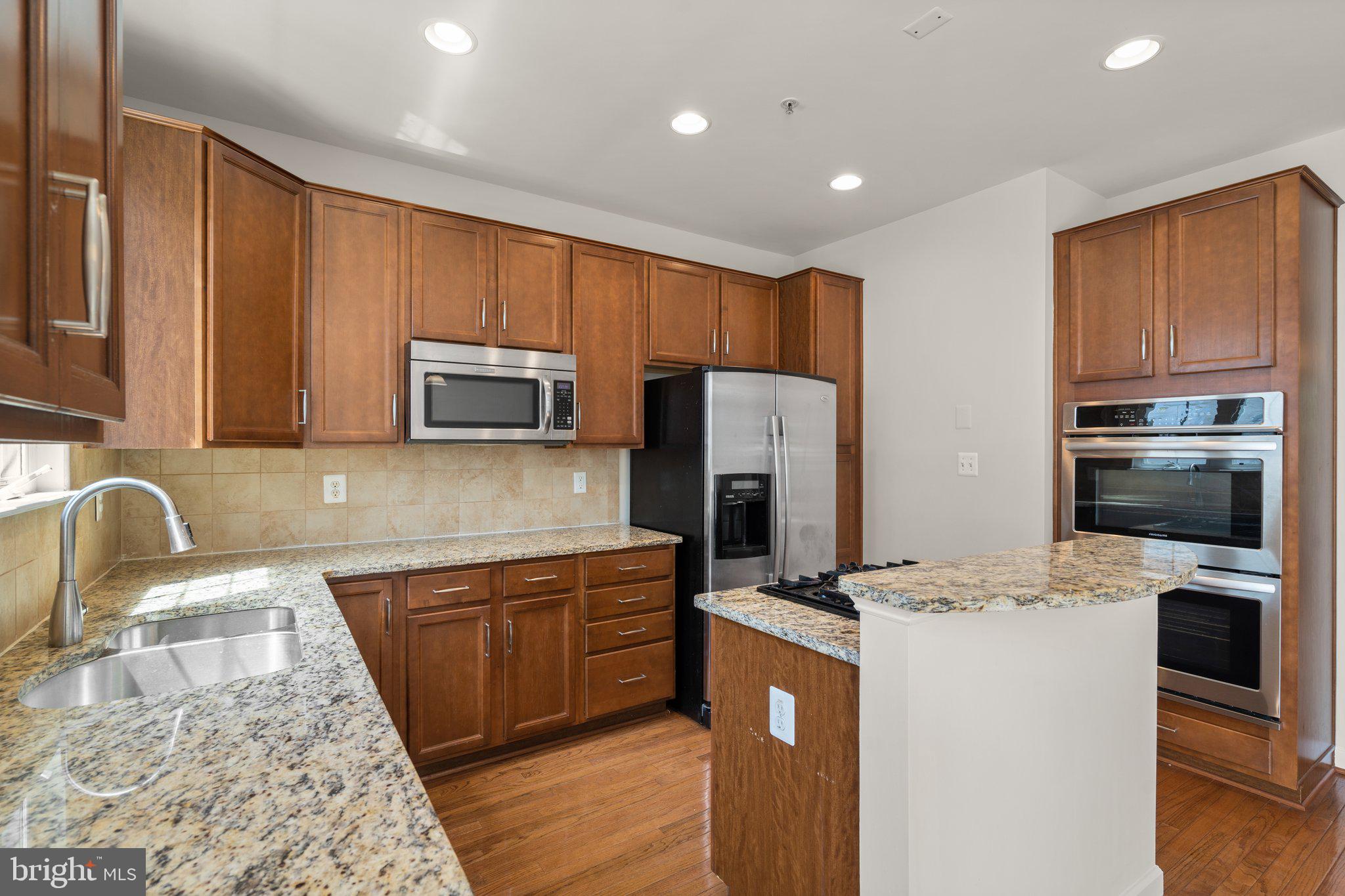11669 Leesborough Circle Silver Spring, MD 20902 - Photo 16 of 46 a kitchen with kitchen island granite countertop stainless steel appliances cabinets a sink and a counter top space