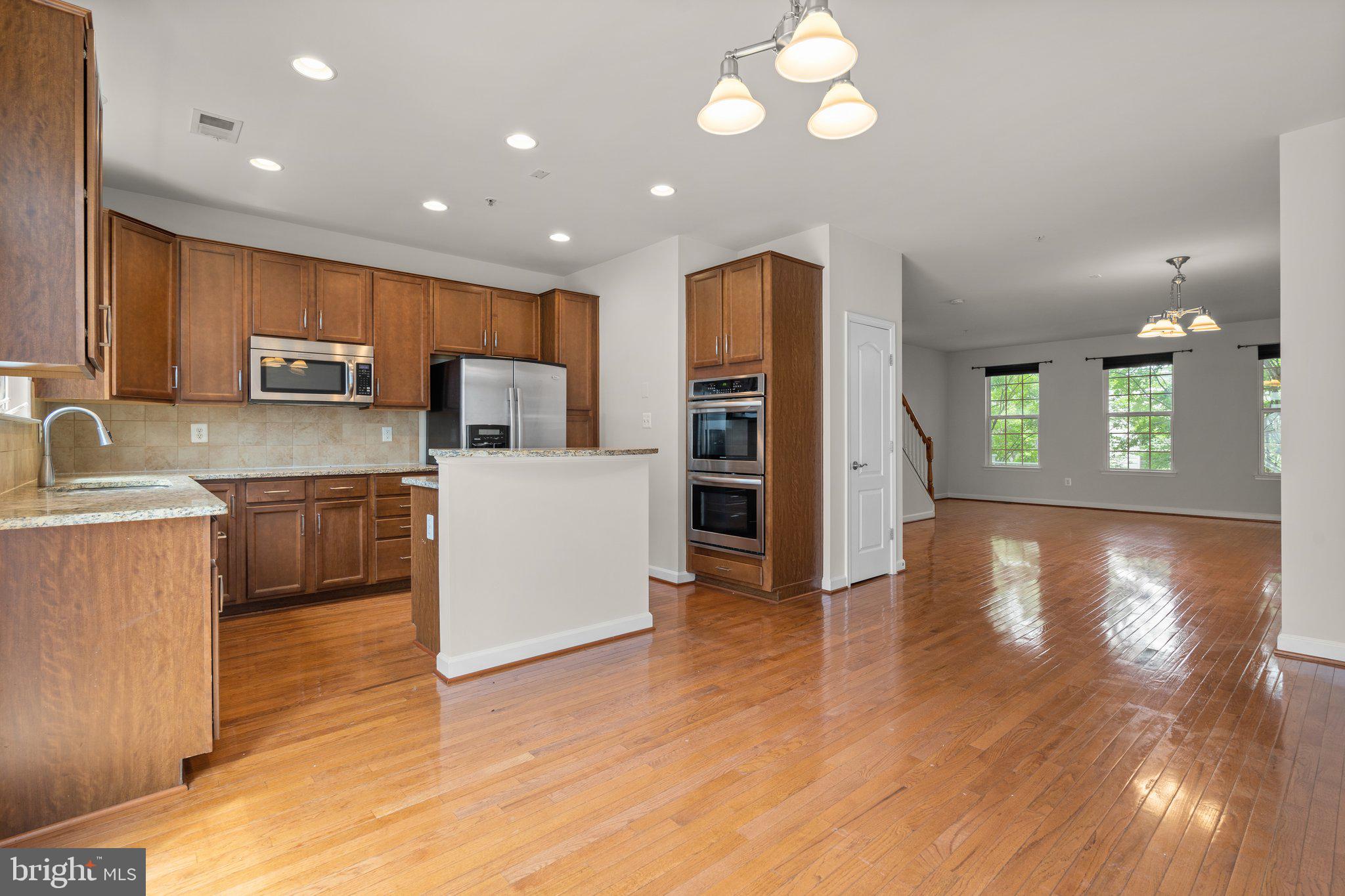 11669 Leesborough Circle Silver Spring, MD 20902 - Photo 9 of 46 a kitchen with a refrigerator a stove top oven and a sink with wooden floor