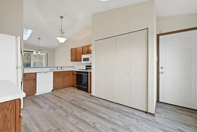 a kitchen with stainless steel appliances granite countertop a refrigerator a sink dishwasher a stove and a refrigerator with wooden floor