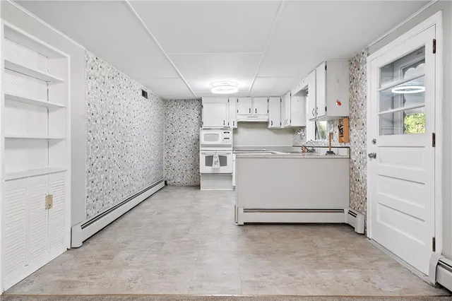 a view of a kitchen with white cabinets and wooden floor