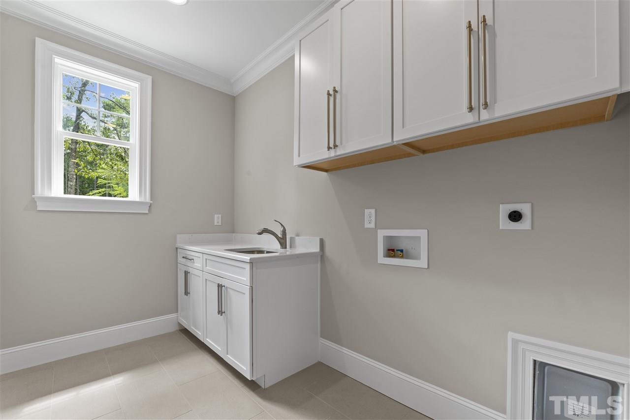 11007 Crest Mist Circle Raleigh, NC 27613 - Photo 17 of 30 The spacious and bright laundry room is in the back on the main floor by the guest suite. It has upper and lower cabinets and a sink.
