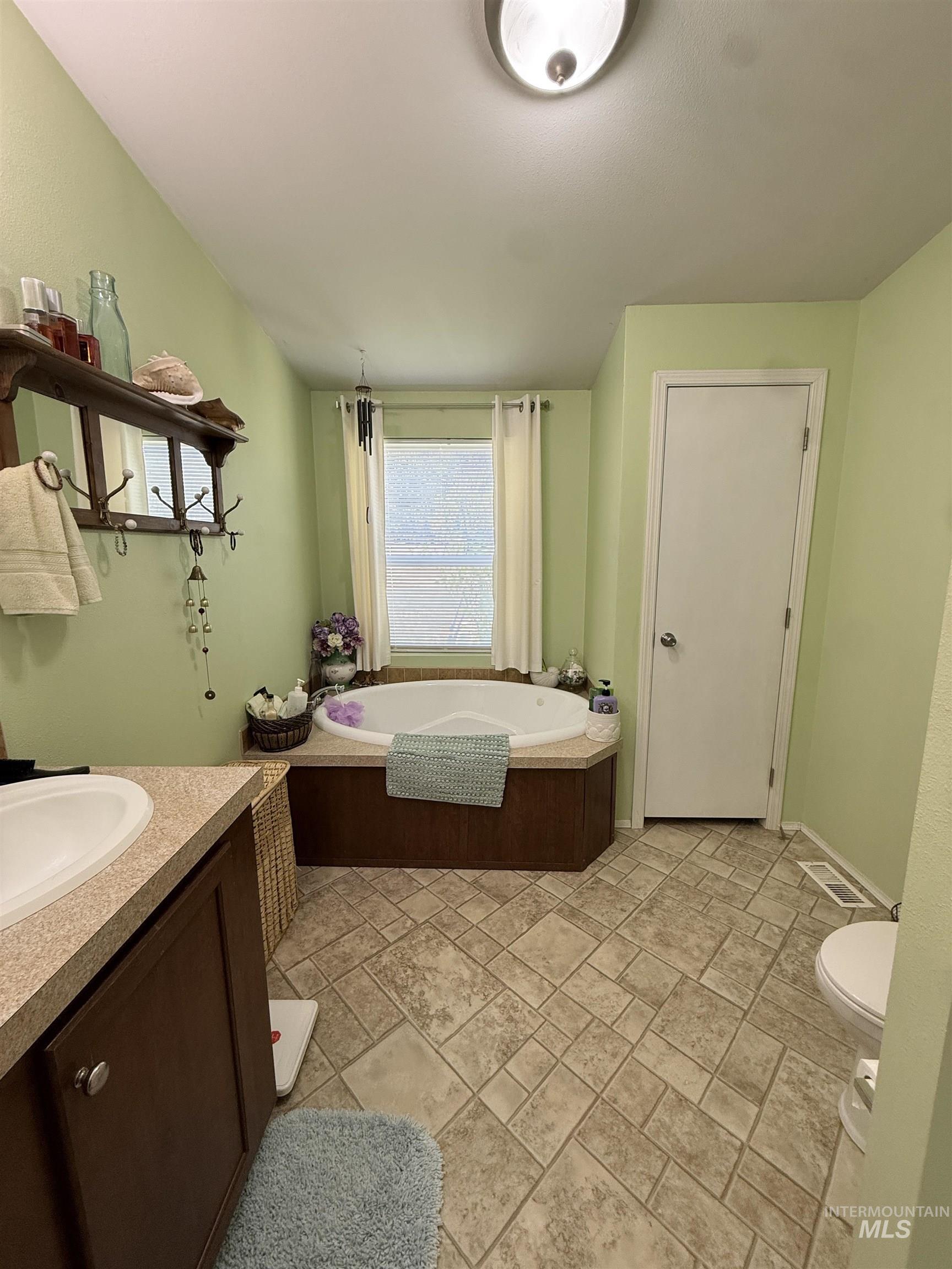 2750 Alden Road, Unit 12 12 Fruitland, ID 83619 - Photo 22 of 38 Carpeted bedroom featuring a ceiling fan with integrated lighting, a mirrored wall accent, and a visible doorway leading to a bathroom with a vanity and sink