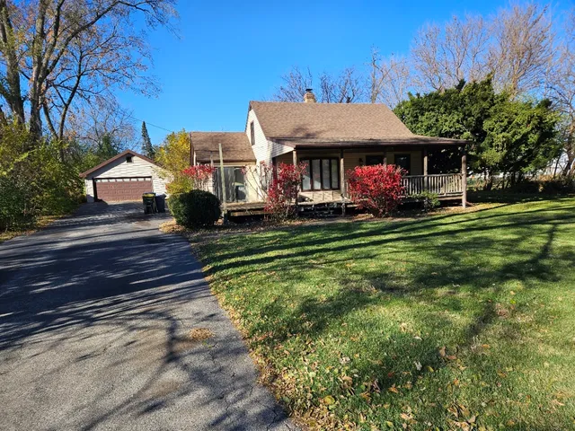a view of a big house with table and chairs under an umbrella