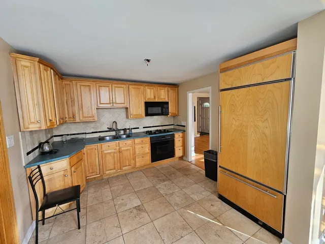 a kitchen with granite countertop a refrigerator a sink a stove a dining table and chairs