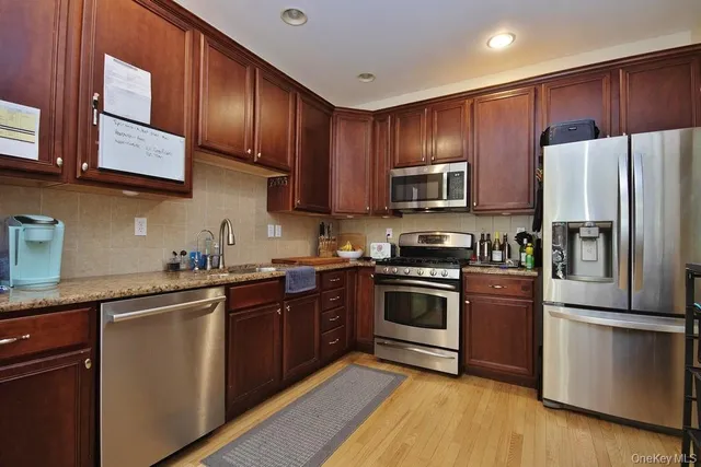 a kitchen with granite countertop wooden cabinets stainless steel appliances and a sink