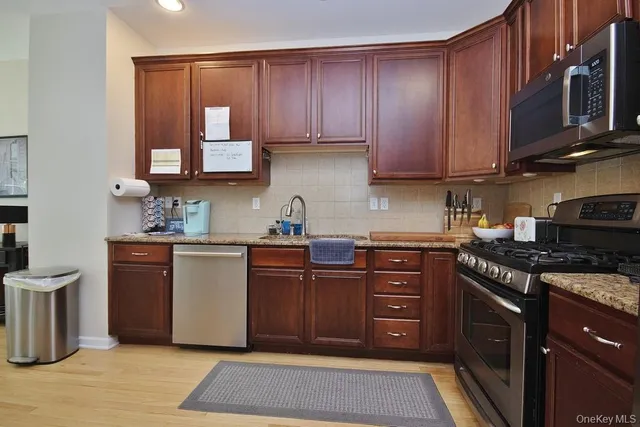 a kitchen with stainless steel appliances granite countertop a stove a sink dishwasher and a microwave oven with large cabinets