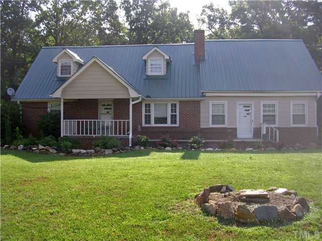 a view of a house with a big yard potted plants and large tree