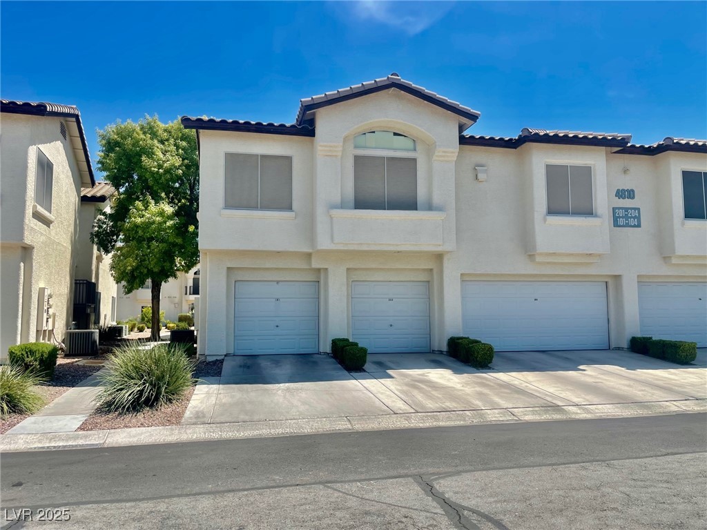 4810 Grey Wolf Lane, Unit 101 Las Vegas, NV 89149 - Photo 7 of 7 Mediterranean / spanish house featuring a garage, concrete driveway, stucco siding, and a tile roof
