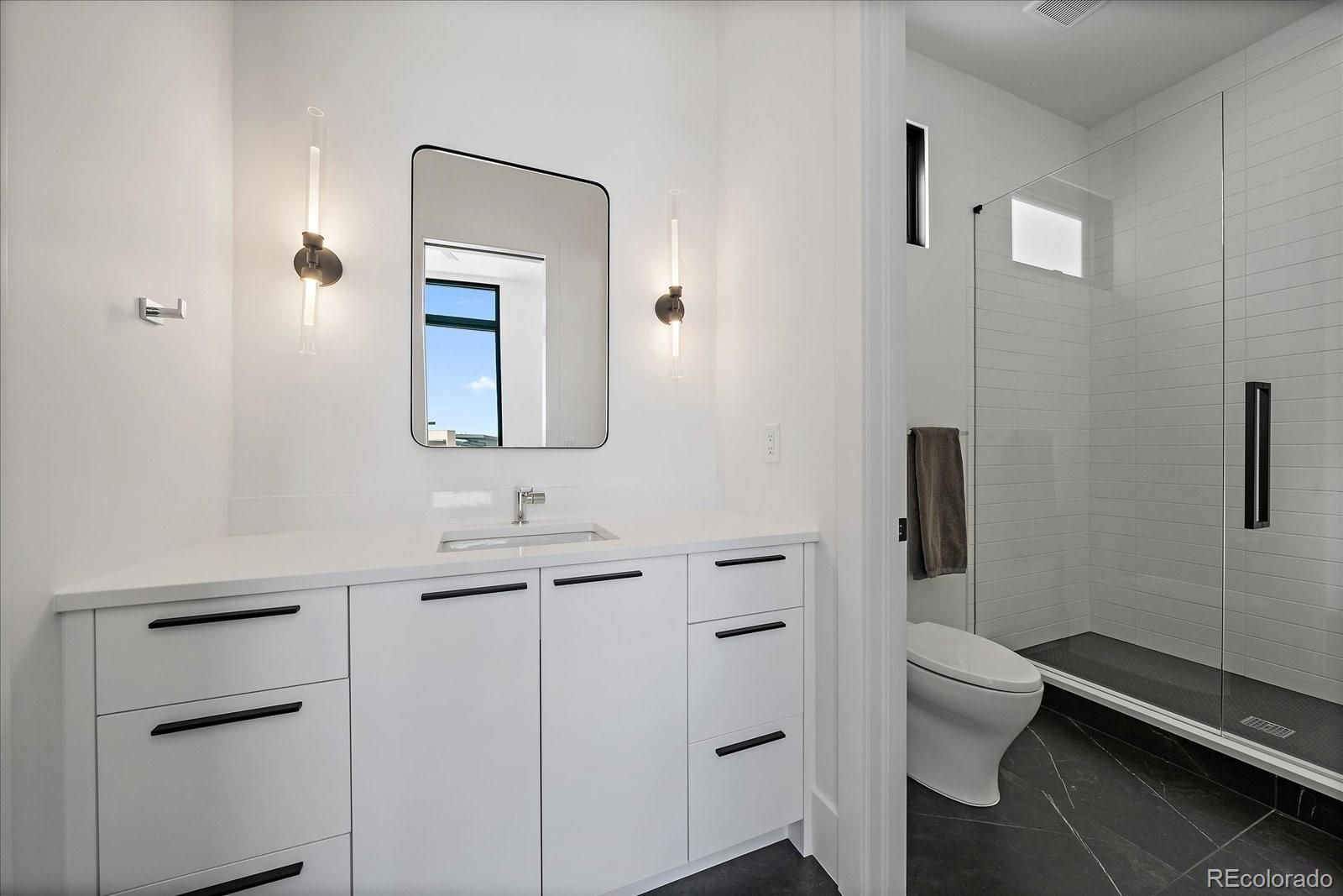 5263 Creation Rock Trail Morrison, CO 80465 - Photo 26 of 50 a bathroom with a toilet a sink and mirror