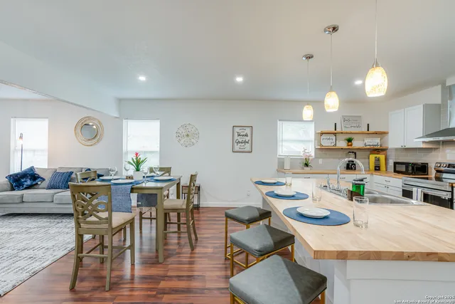 a kitchen with a sink a stove a refrigerator and white cabinets with wooden floor