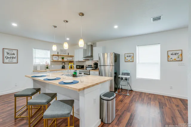a kitchen with a stove a sink a refrigerator and white cabinets with wooden floor